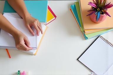 Person taking notes and organizing study materials.